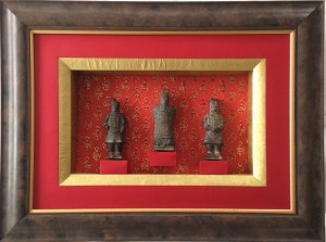 Encadrement de trois statuettes de guerriers chinois. Utilisation de différents papiers rouge, doré et à motif doré.